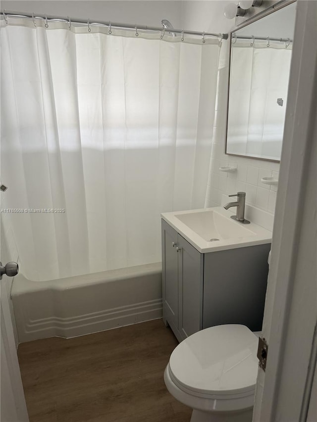 bathroom with decorative backsplash, wood finished floors, toilet, vanity, and shower / bathtub combination with curtain