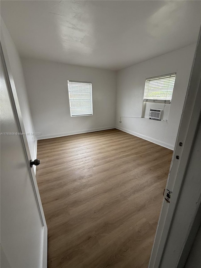 empty room with baseboards, cooling unit, and dark wood-style flooring