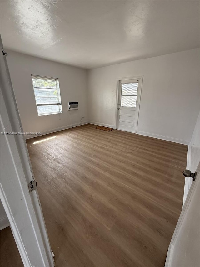 spare room featuring baseboards and wood finished floors