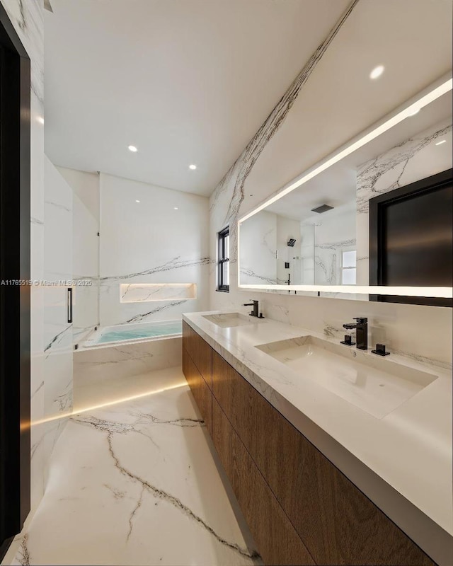 bathroom featuring a sink, a marble finish shower, a tub with marble appearance, and double vanity