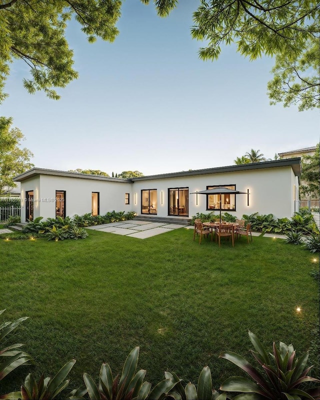 back of property featuring stucco siding, a patio, a lawn, and fence