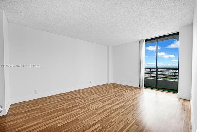 3300 NE 191st St Unit Lp03, Aventura, FL 33180 - empty room featuring floor to ceiling windows, wood finished floors, a textured ceiling, and baseboards