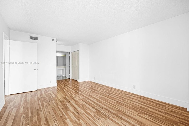 3300 NE 191st St Unit Lp03, Aventura, FL 33180 - unfurnished bedroom featuring light wood-style floors, baseboards, a textured ceiling, and ensuite bath