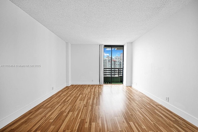 3300 NE 191st St Unit Lp03, Aventura, FL 33180 - empty room with a textured ceiling, wood finished floors, floor to ceiling windows, and baseboards