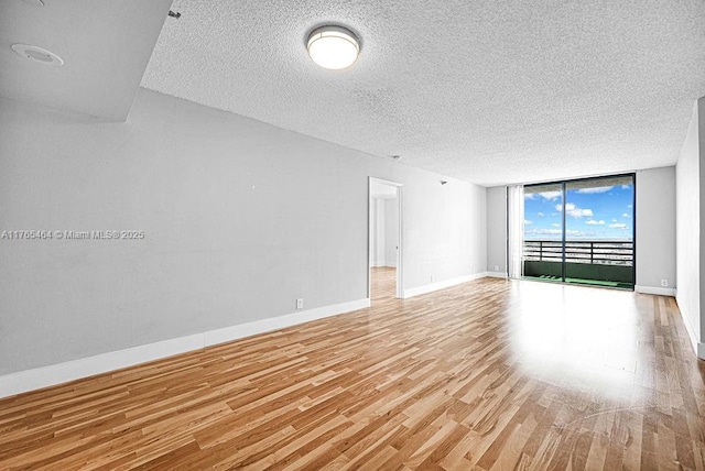 3300 NE 191st St Unit Lp03, Aventura, FL 33180 - empty room featuring expansive windows, a textured ceiling, light wood-style flooring, and baseboards