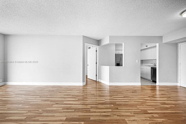 3300 NE 191st St Unit Lp03, Aventura, FL 33180 - unfurnished living room with a textured ceiling, light wood-style floors, baseboards, and a sink