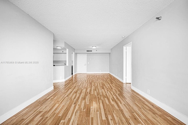 3300 NE 191st St Unit Lp03, Aventura, FL 33180 - unfurnished living room featuring a textured ceiling, light wood finished floors, and baseboards