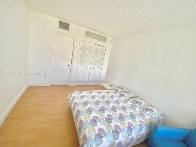 9801 Collins Ave Unit 8M, Bal Harbour, FL 33154 - bedroom with light wood-style floors and a textured ceiling