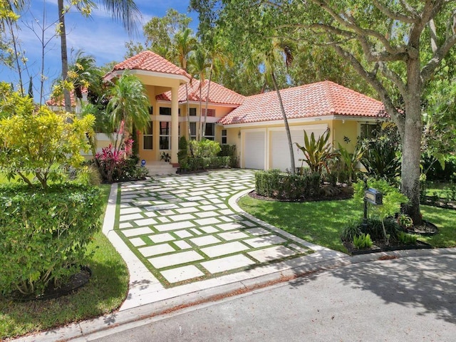 mediterranean / spanish house with an attached garage, a front lawn, stucco siding, and a tile roof