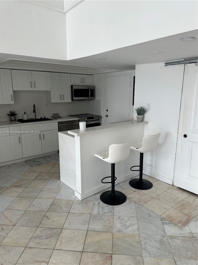 18041 Biscayne Blvd Unit Ph02, Aventura, FL 33160 - kitchen featuring a sink, backsplash, a kitchen bar, appliances with stainless steel finishes, and a peninsula