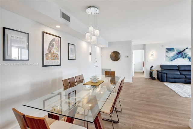 dining space with visible vents, an inviting chandelier, baseboards, and light wood-style floors