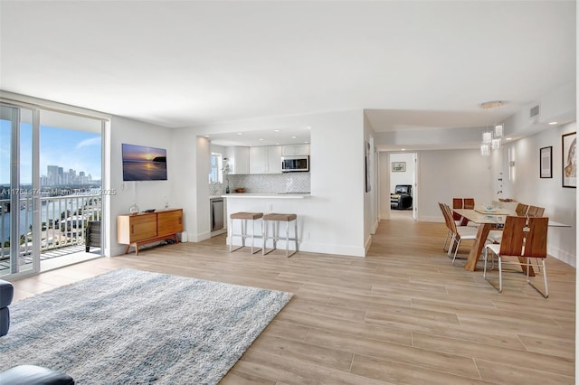 living area featuring light wood finished floors, baseboards, and expansive windows