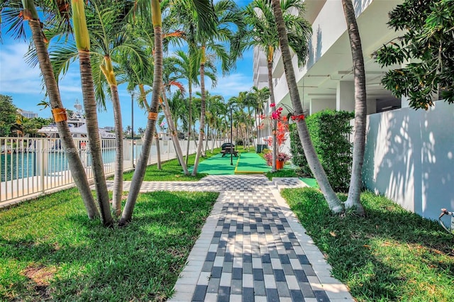 view of home's community with shuffleboard, fence, and a lawn