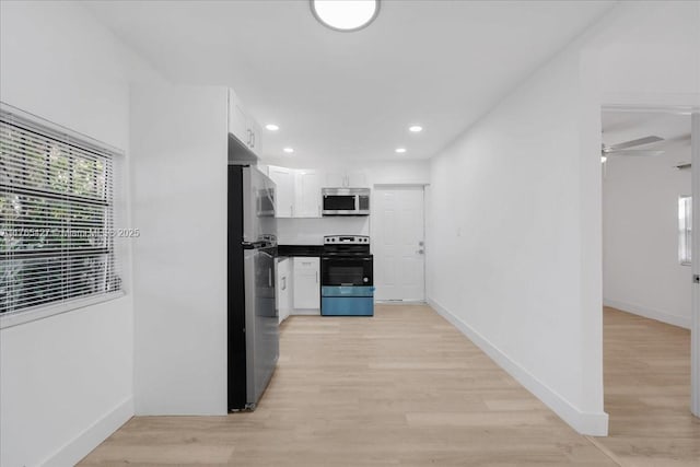 2911 NW 30th St, Miami, FL 33142 - kitchen featuring white cabinets, light wood-style floors, baseboards, and appliances with stainless steel finishes