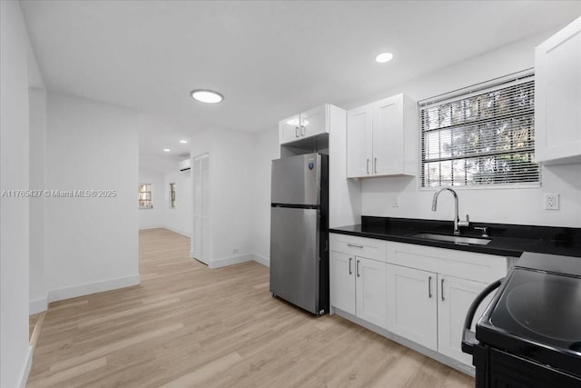2911 NW 30th St, Miami, FL 33142 - kitchen with black range with electric cooktop, light wood-style flooring, freestanding refrigerator, white cabinetry, and a sink
