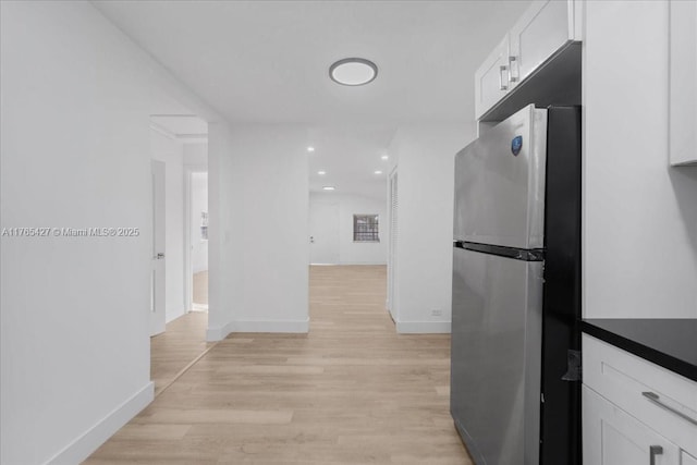 2911 NW 30th St, Miami, FL 33142 - kitchen featuring dark countertops, freestanding refrigerator, light wood-style floors, white cabinets, and baseboards