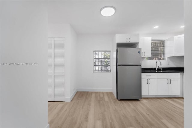2911 NW 30th St, Miami, FL 33142 - kitchen with light wood finished floors, freestanding refrigerator, a sink, white cabinets, and dark countertops