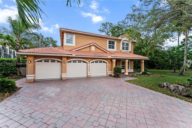 mediterranean / spanish home featuring a tiled roof, covered porch, stucco siding, decorative driveway, and a garage