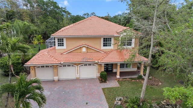 mediterranean / spanish home featuring a porch, a tiled roof, decorative driveway, and stucco siding