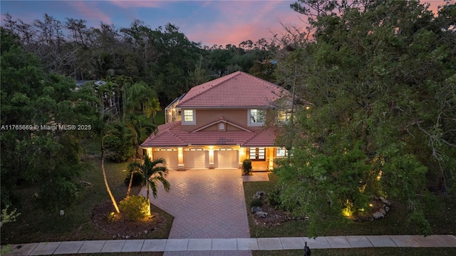mediterranean / spanish home featuring stucco siding, driveway, and a tile roof