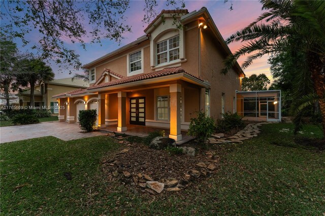 mediterranean / spanish-style home featuring stucco siding, driveway, a front yard, and french doors