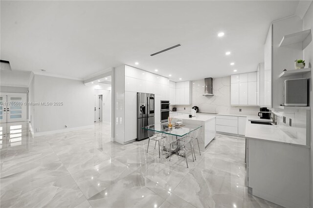 kitchen featuring appliances with stainless steel finishes, white cabinetry, wall chimney exhaust hood, modern cabinets, and marble finish floor