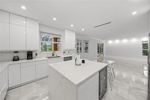 kitchen featuring wine cooler, a center island, modern cabinets, and a sink