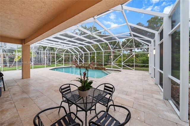 outdoor pool featuring glass enclosure and a patio