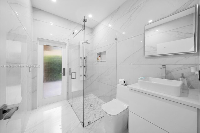 bathroom with a marble finish shower, toilet, tile walls, and vanity