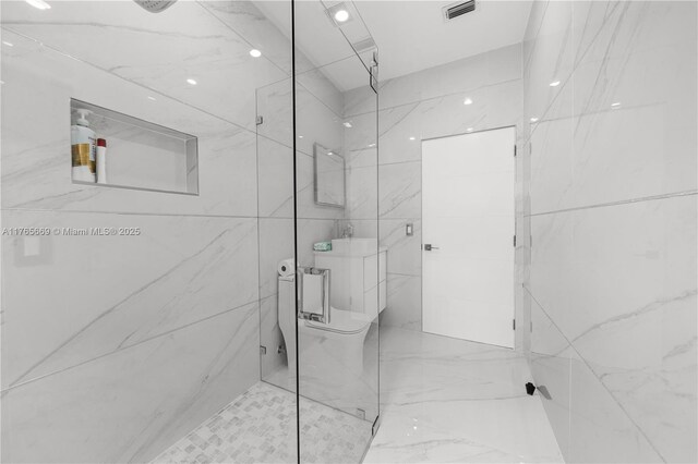full bathroom with a marble finish shower, visible vents, and toilet