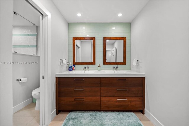 full bathroom featuring double vanity, tile patterned flooring, toilet, and a sink