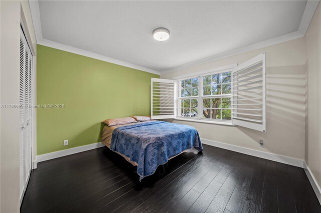 bedroom with crown molding, a closet, baseboards, and wood-type flooring