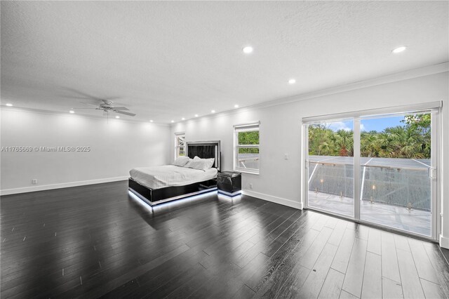 unfurnished bedroom featuring baseboards, dark wood-type flooring, a textured ceiling, crown molding, and access to outside