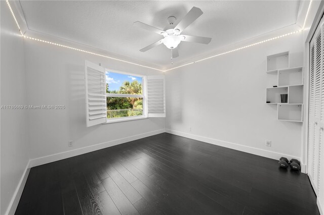 unfurnished room with a ceiling fan, dark wood-style floors, and baseboards