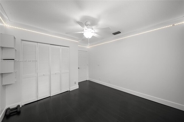 unfurnished bedroom with visible vents, ceiling fan, baseboards, a closet, and dark wood-style flooring