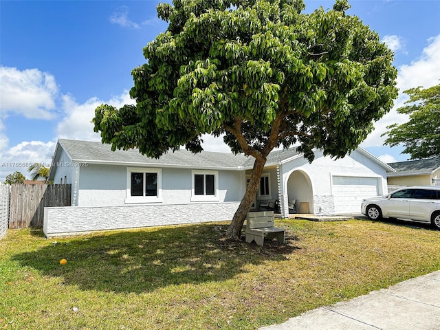single story home featuring a front yard, stucco siding, fence, and an attached garage