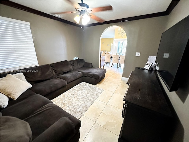 living area with light tile patterned floors, arched walkways, ornamental molding, and a ceiling fan