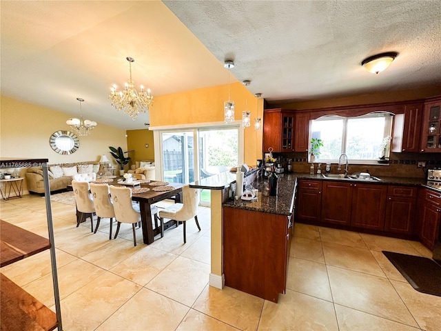 kitchen with a sink, a chandelier, a peninsula, glass insert cabinets, and light tile patterned floors