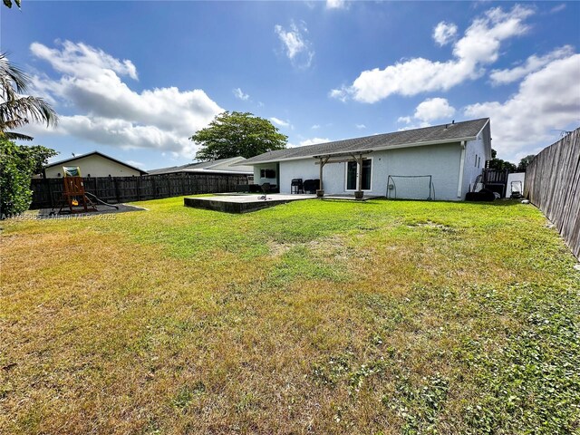 back of house with a fenced backyard, stucco siding, a yard, and a patio area