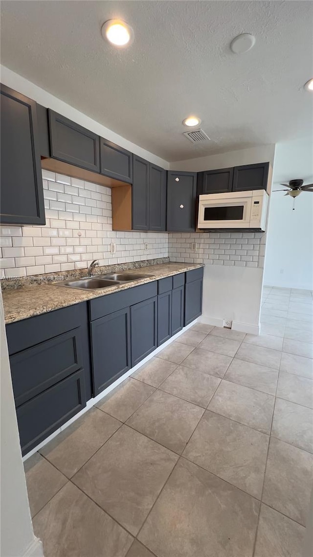 607 N 19th St, Fort Pierce, FL 34950 - kitchen featuring white microwave, visible vents, backsplash, light tile patterned floors, and a sink