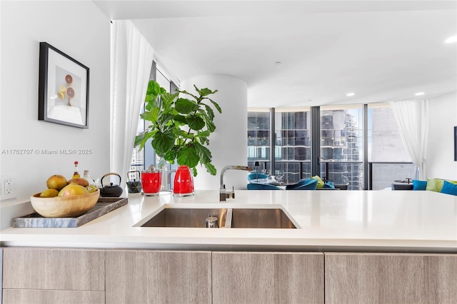 kitchen featuring a wealth of natural light, modern cabinets, light brown cabinetry, and a sink