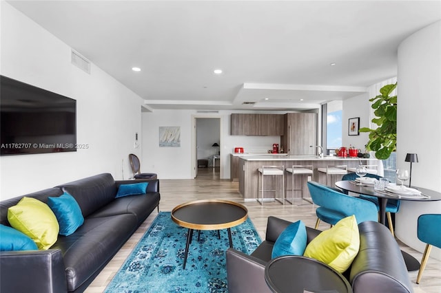 living area with recessed lighting, visible vents, and light wood finished floors