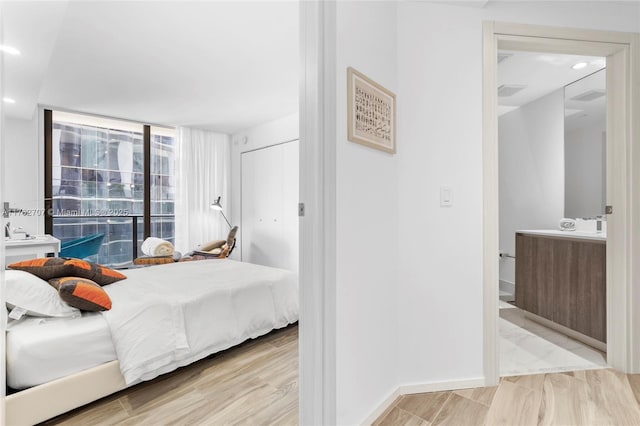 bedroom featuring floor to ceiling windows, recessed lighting, wood finished floors, and baseboards