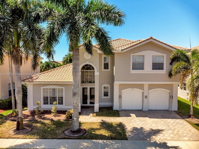 mediterranean / spanish-style home featuring decorative driveway, stucco siding, a tiled roof, and french doors