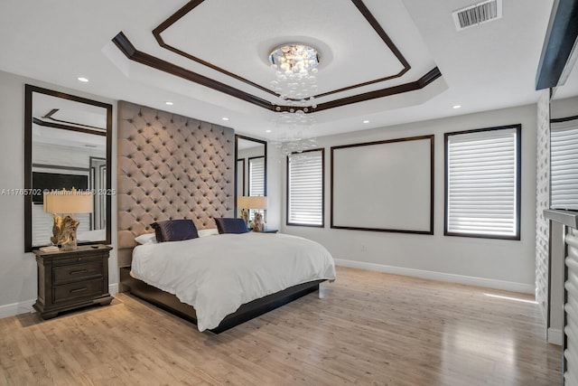 bedroom featuring a tray ceiling, visible vents, and crown molding