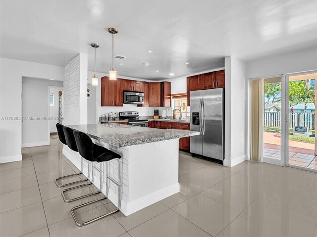 4401 Johnson St, Hollywood, FL 33021 - kitchen with light stone countertops, pendant lighting, appliances with stainless steel finishes, a peninsula, and light tile patterned flooring