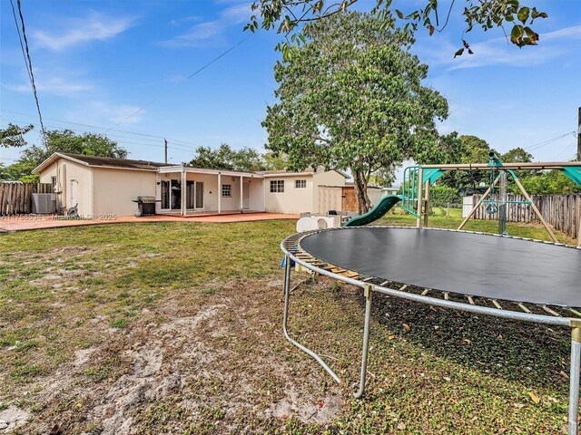 4401 Johnson St, Hollywood, FL 33021 - view of yard featuring a fenced backyard, central air condition unit, a playground, a trampoline, and a patio area