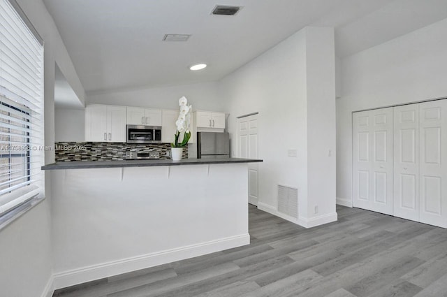 1627 Cypress Pointe Dr Unit 2-1, Coral Springs, FL 33071 - kitchen with stainless steel appliances, lofted ceiling, dark countertops, white cabinetry, and a peninsula