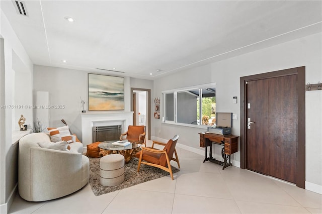 living room featuring a glass covered fireplace, light tile patterned floors, baseboards, visible vents, and recessed lighting