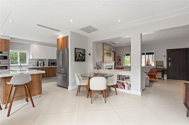 dining space featuring a fireplace, recessed lighting, and light tile patterned floors